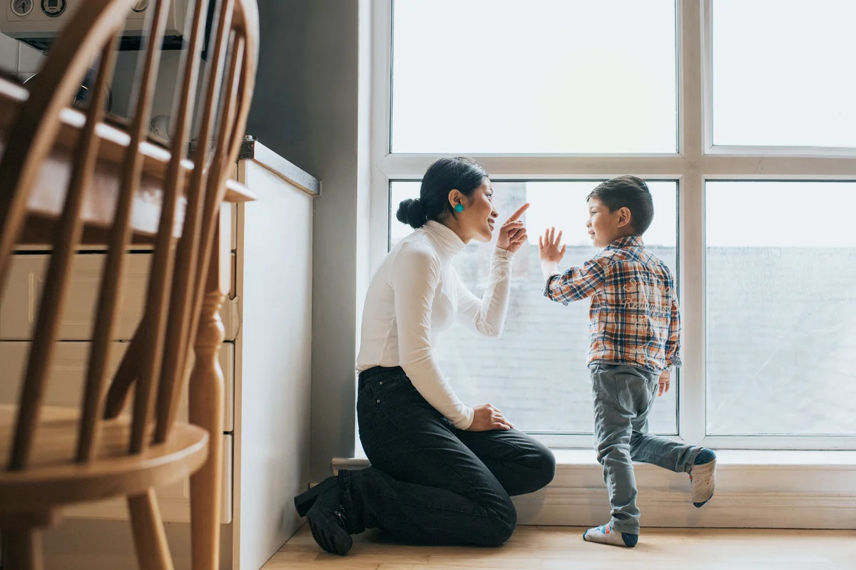 Mother and son talking near large apartment window together