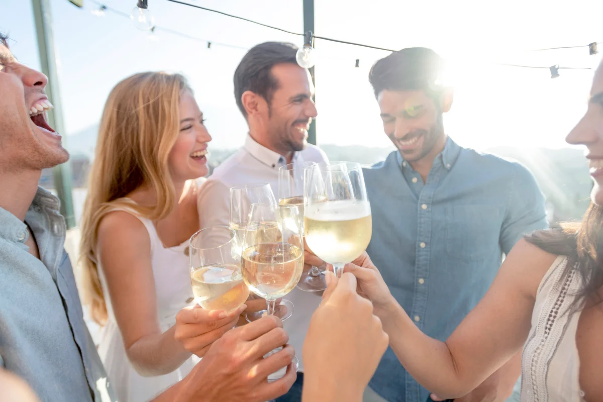 A group of friends toasting and celebrating with white wine outdoors