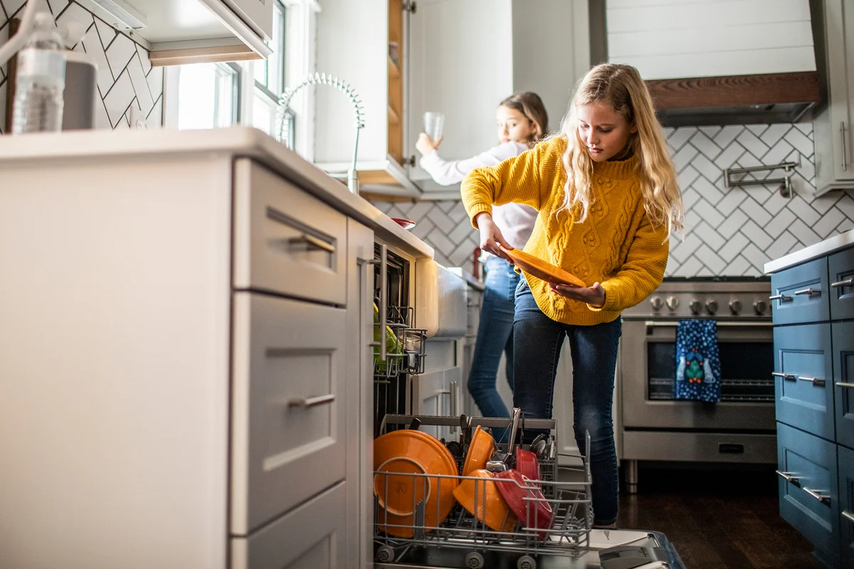 Tween girls doing dishes in modern kitchen