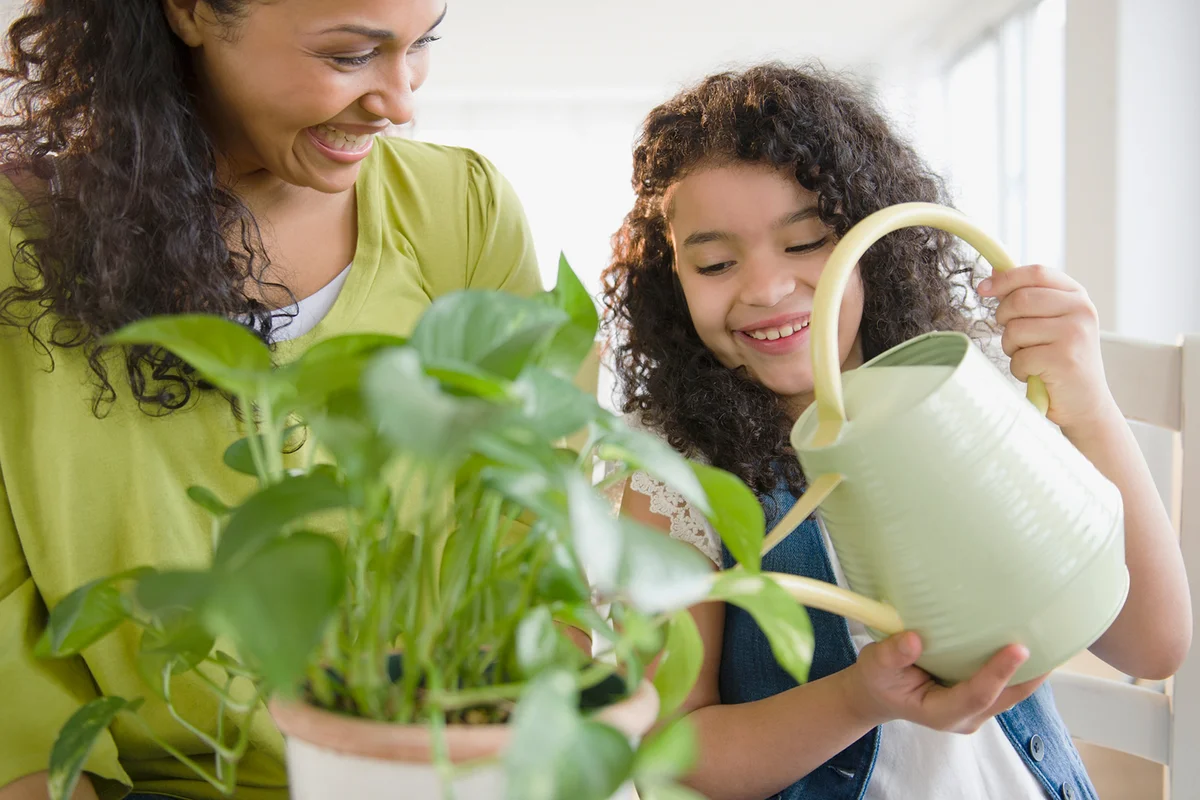 Mother and daughter watering plant together