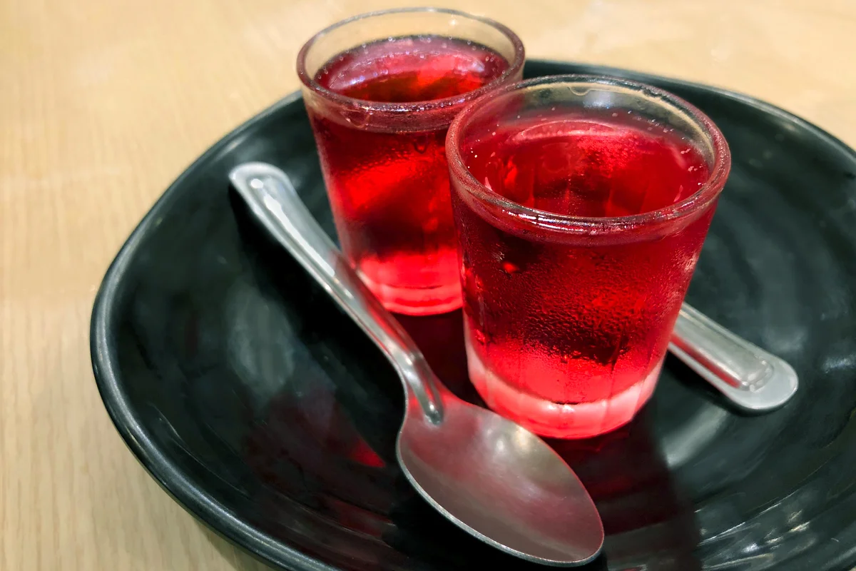 Glasses of red cold jelly pudding serving on black ceramic plate