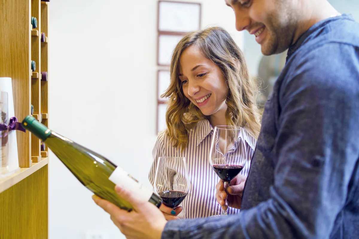 Couple drinking wine and looking at wine label