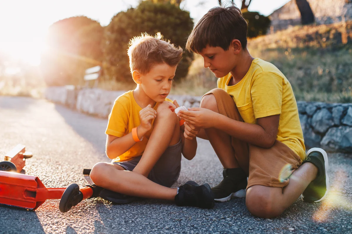 boy helping friend bandage his knee