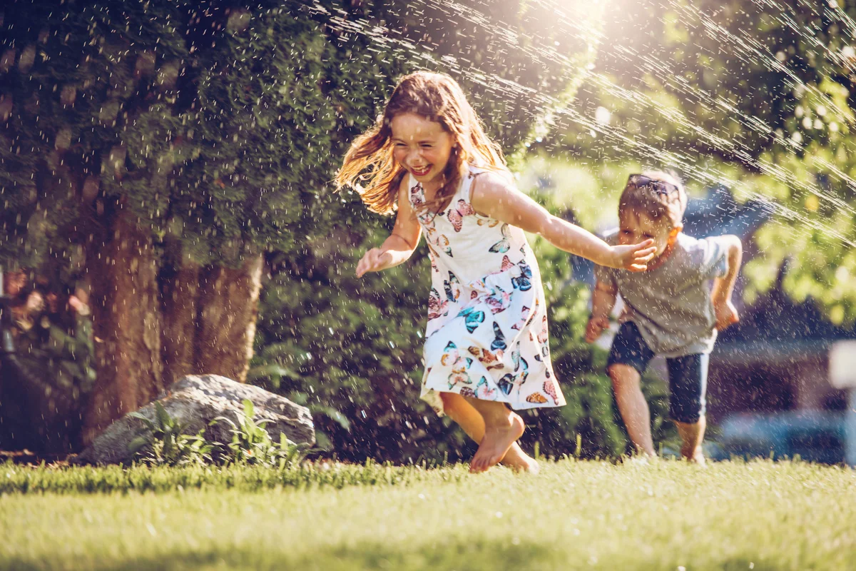 Happy kids playing with garden sprinkler