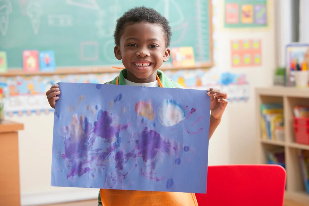 Boy holding painting in art class