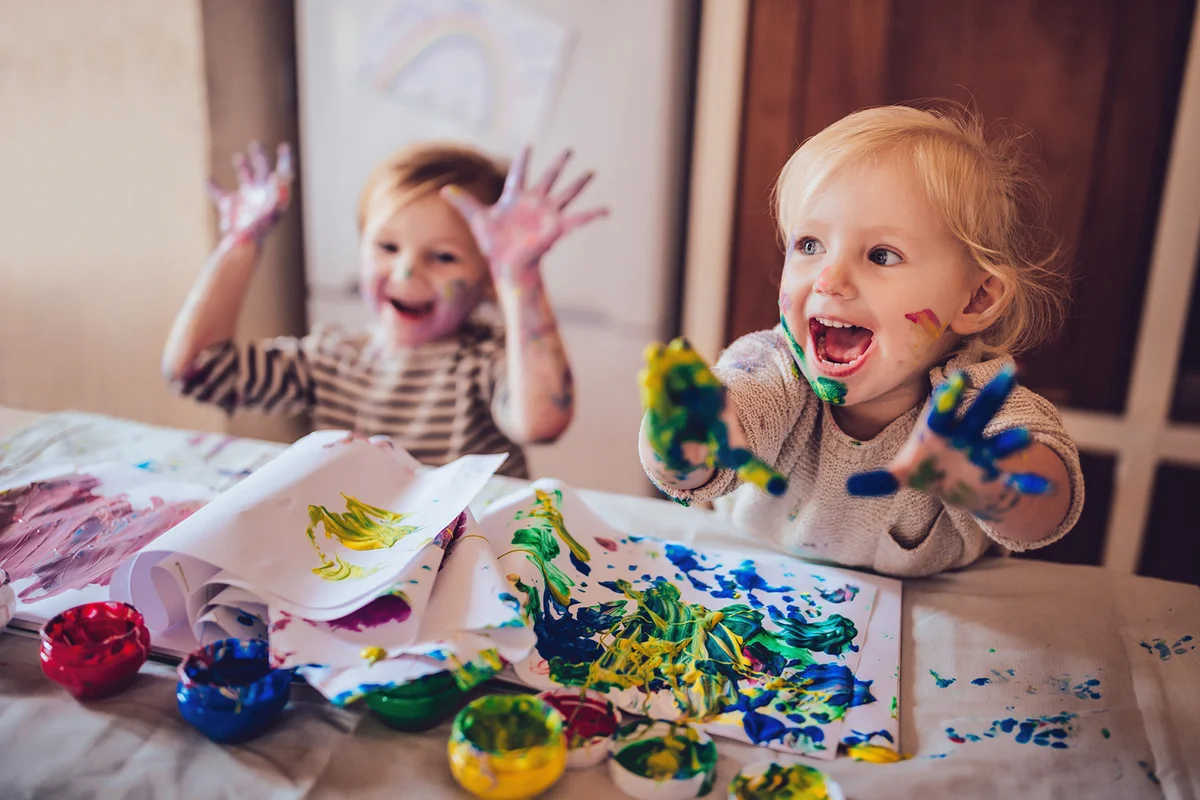 Cheerful little children having fun doing finger painting