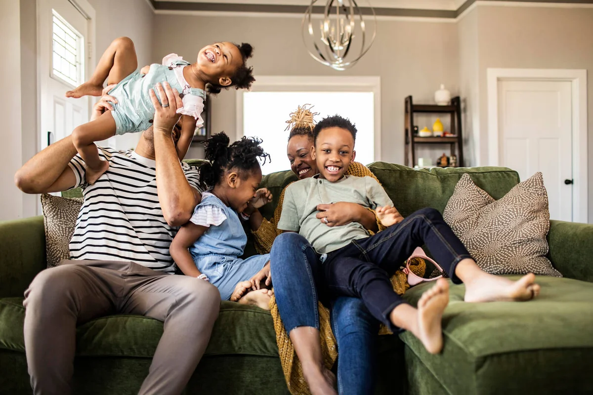 Family of five playing on sofa at home