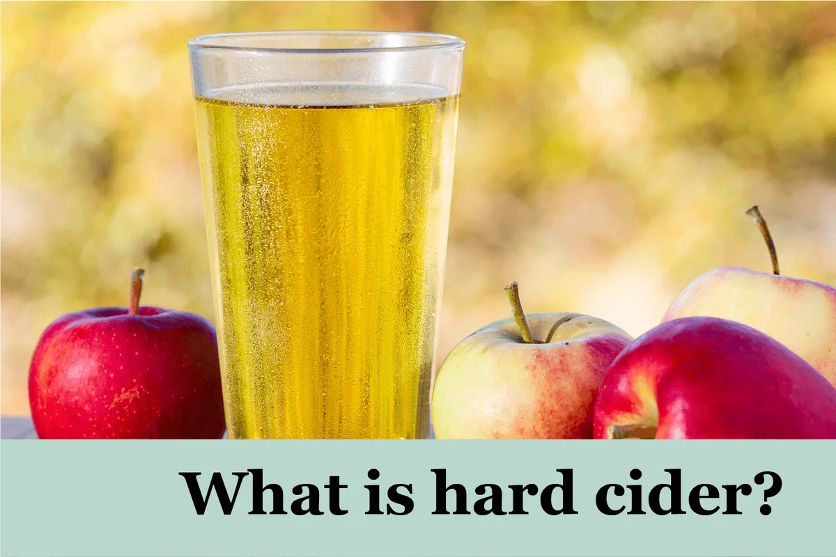 Glass of cider on outdoor table with apples