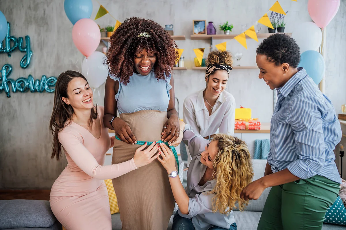 Women friends measuring their pregnant friend's belly