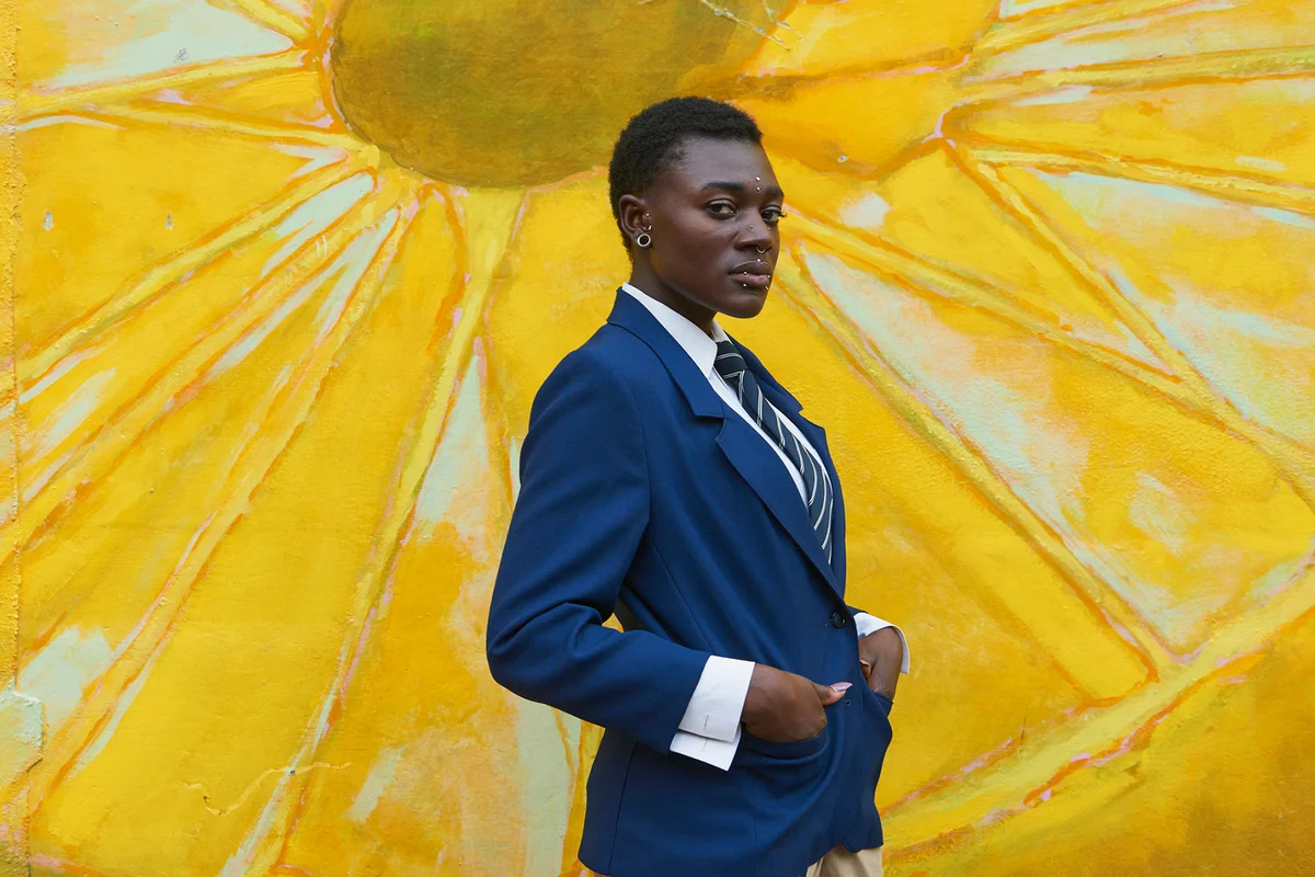 Serious androgynous Black woman standing near mural