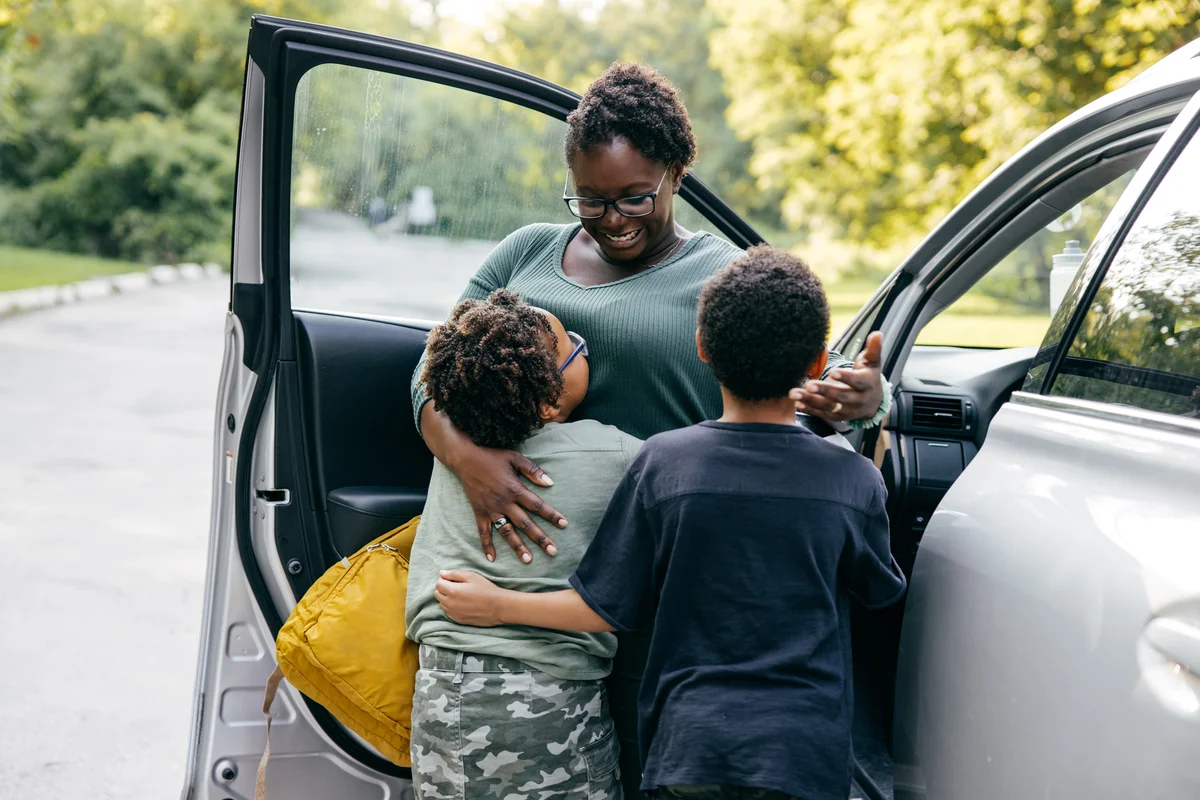 proud mom hugging children on first day of school