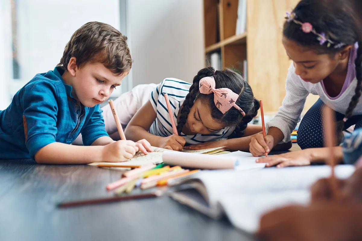 Cropped shot of kids coloring in while lying on the floor