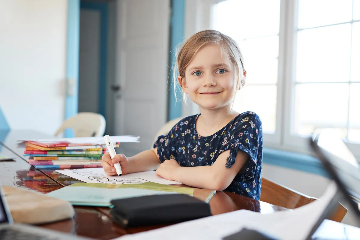 Portrait confident girl doing homework at dining table