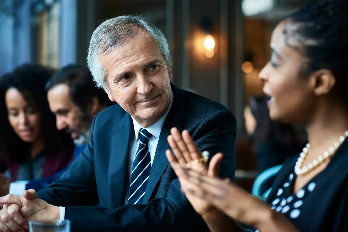 Man listening to young woman at dinner party