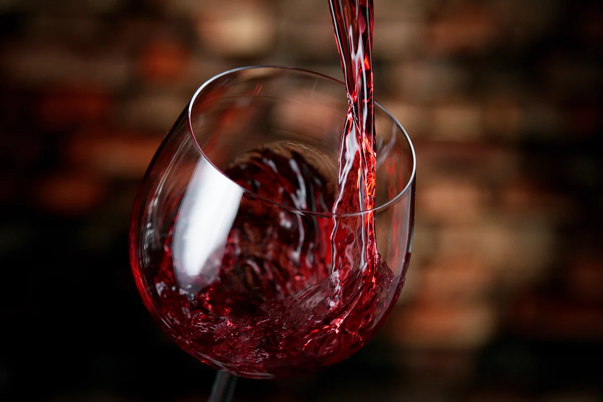 Freeze motion of red wine pouring into glass