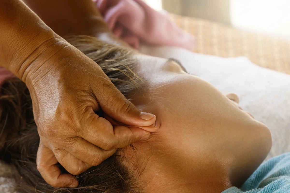 Cropped Hand Of Massage Therapist Massaging Woman Ears At Spa