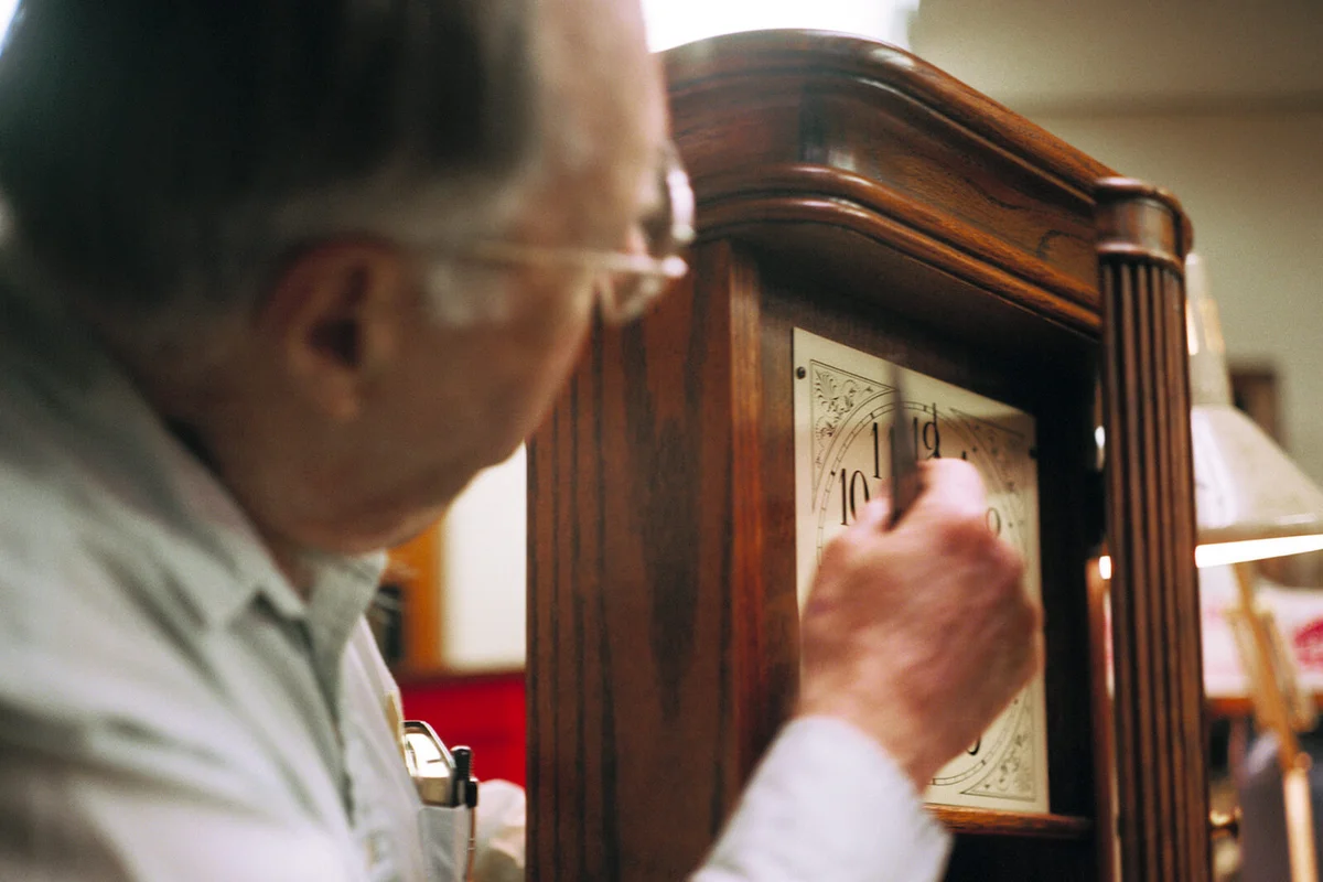 Man Setting Time on Clock in Workshop