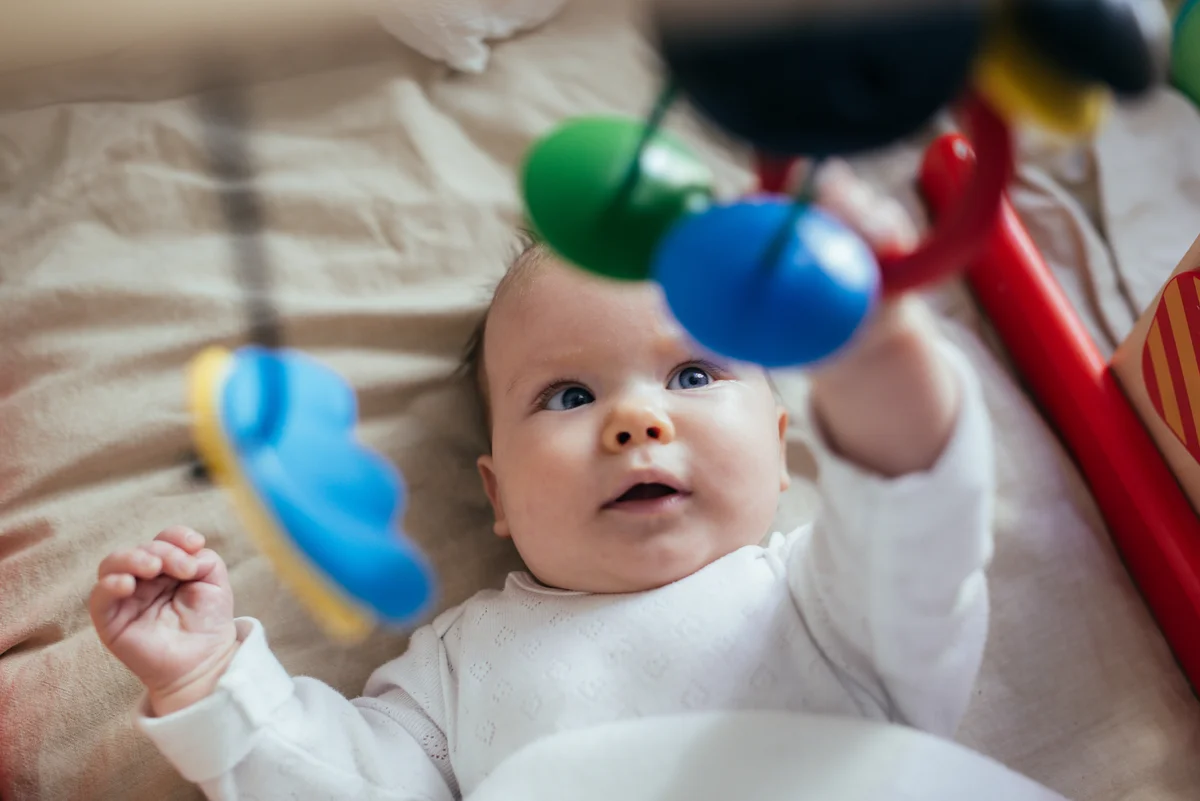 baby boy in crib playing with mobile