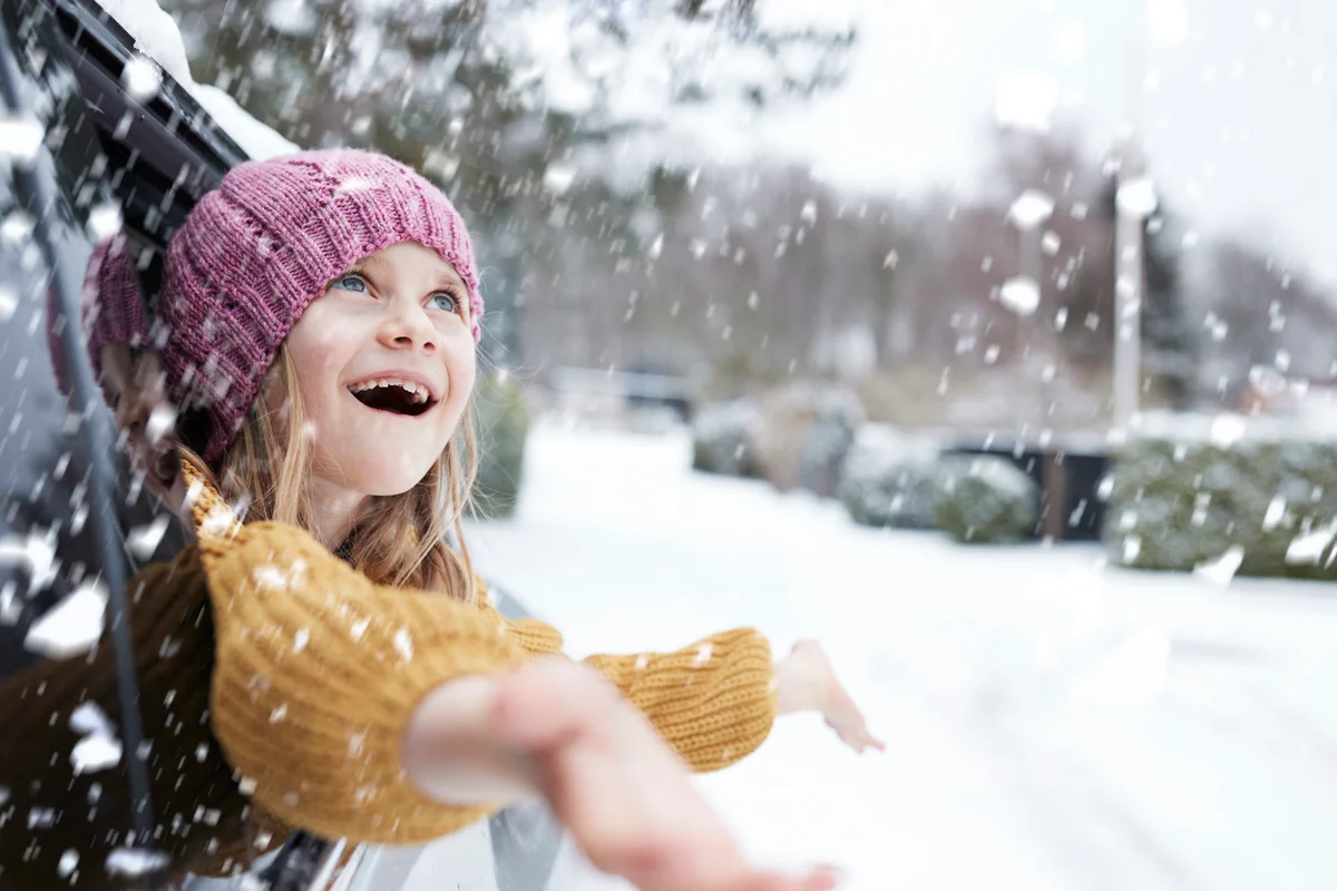 girl leaning out car window catching snowflakes
