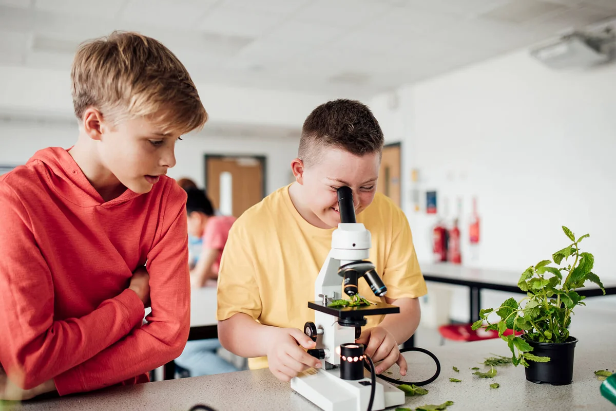 Teenage boy using a microscope to discover in stem class