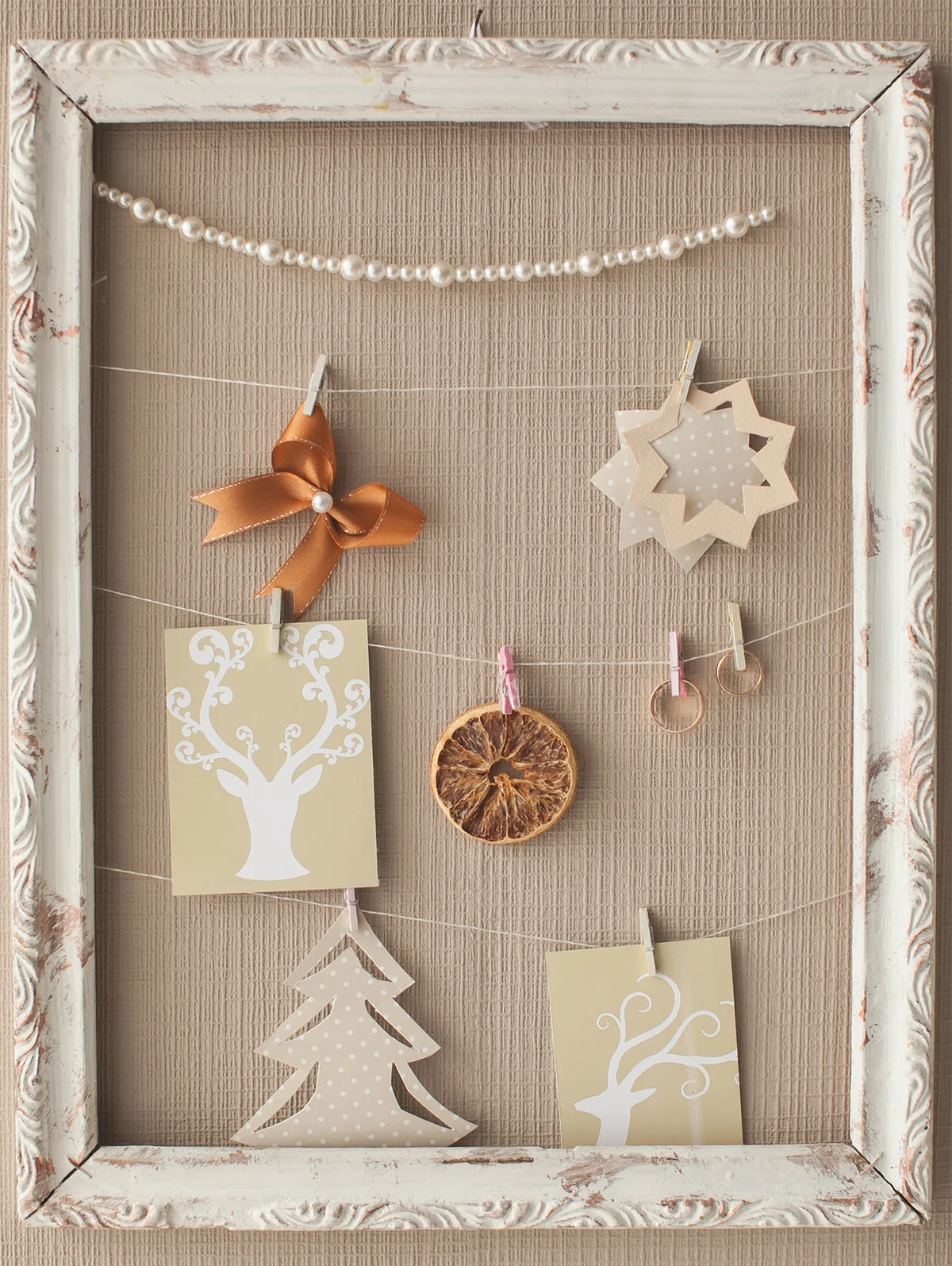 Wedding designer decor in the form of a frame with rings, beads, a bow of satin ribbon, dried orange slice and cut out pictures