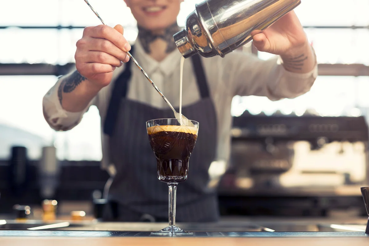 Woman making coffee cocktail at cafe counter