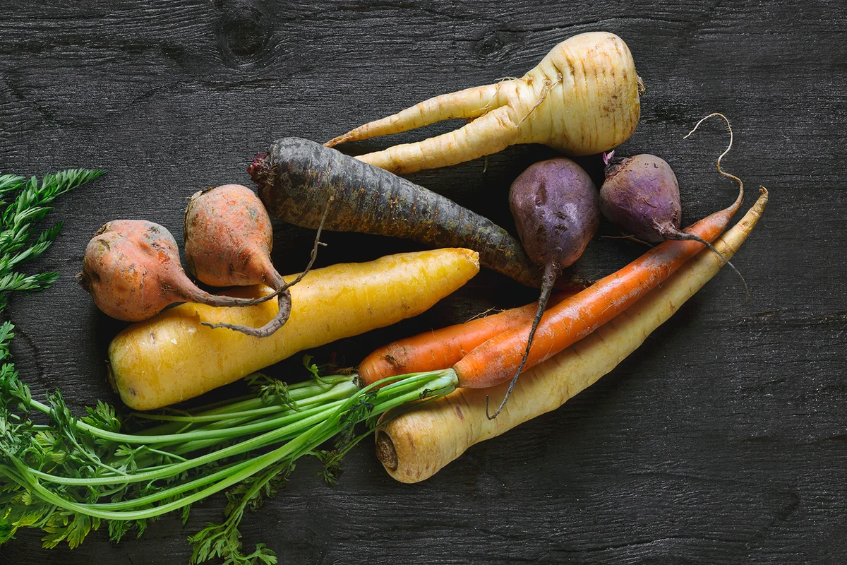 Root vegetables on black background