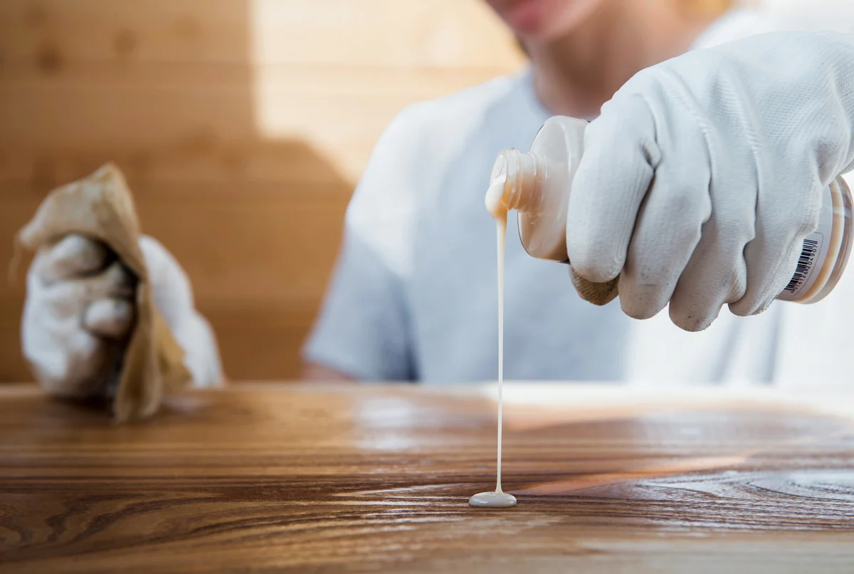 Woman coating wood furniture with oil