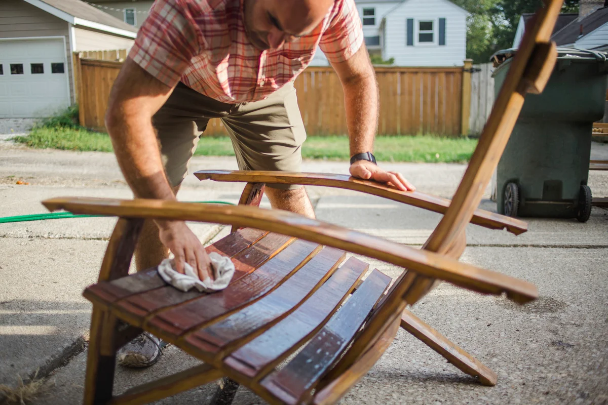 Craftsman polishes a handmade wooden chair outside