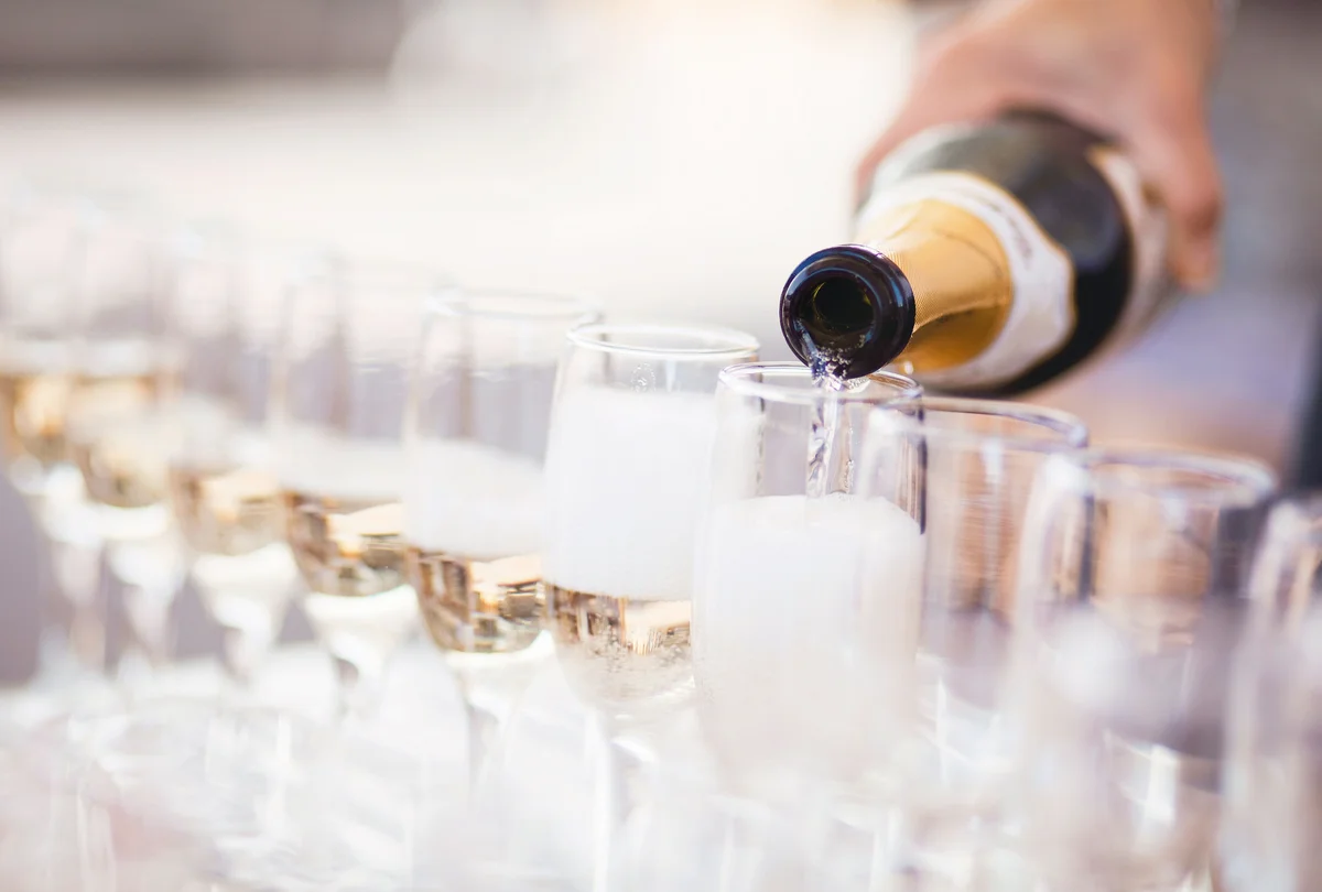 Waiter serving champagne in several glasses