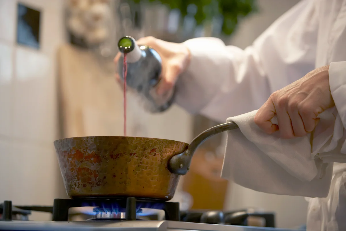 Female Chef Pouring Wine into Pan