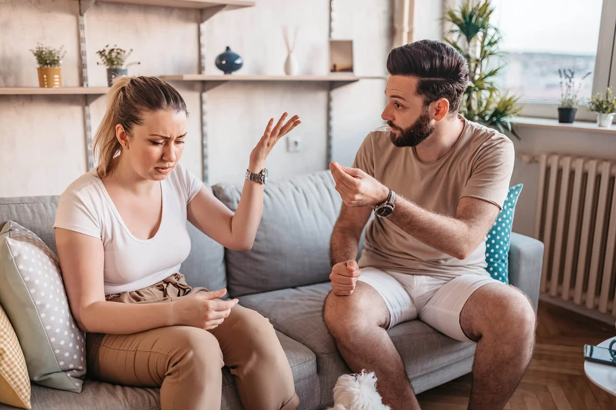 couple are quarreling while sitting on couch at home