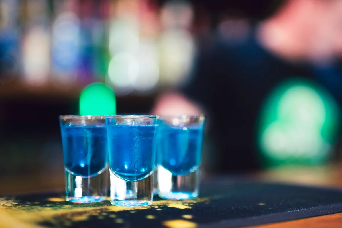Set of several shot glasses filled with vibrant blue shooter cocktail