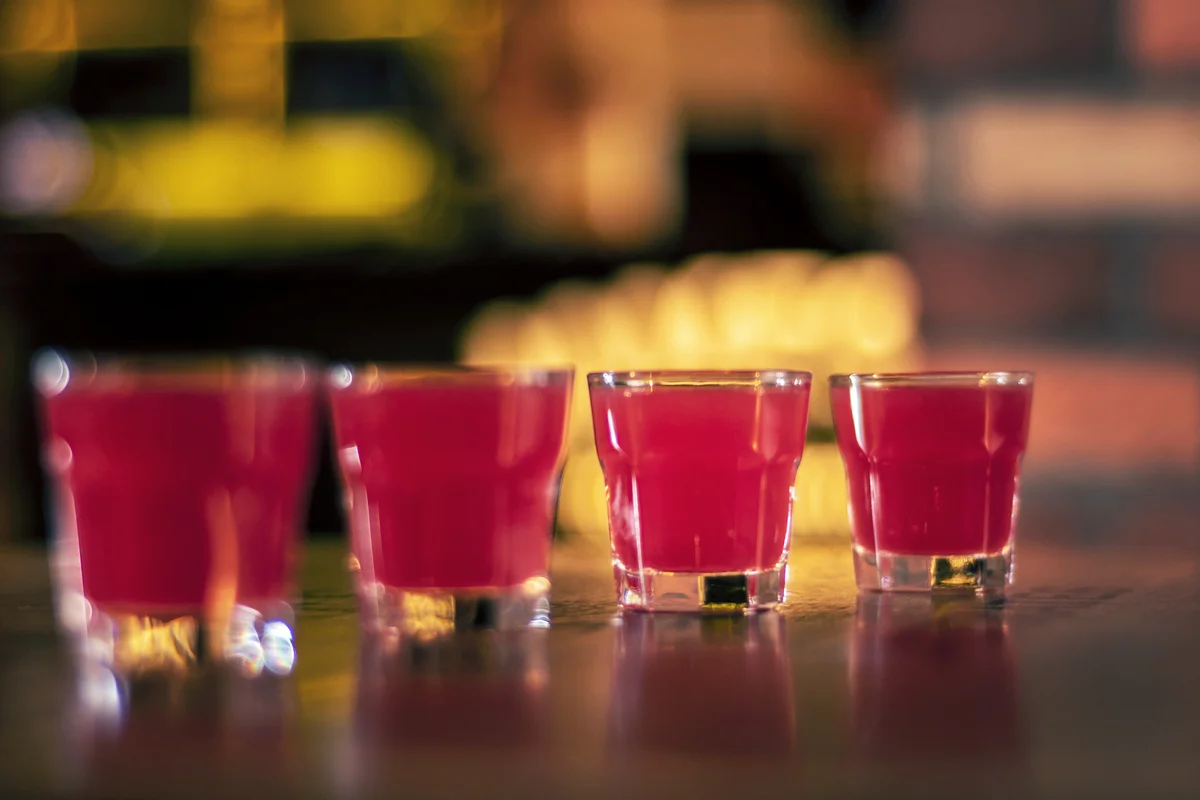 Pink vodka shots on wooden table