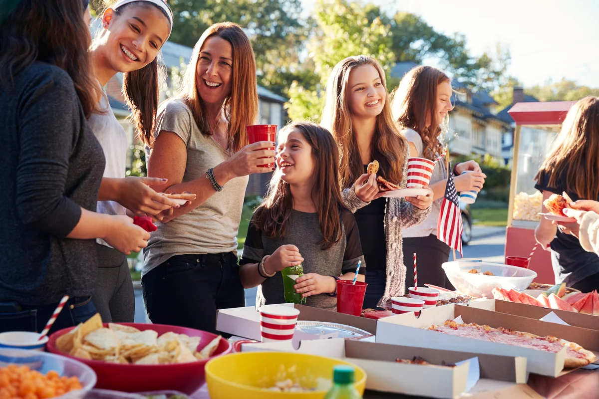 Girls stand talking at a school bash party food table
