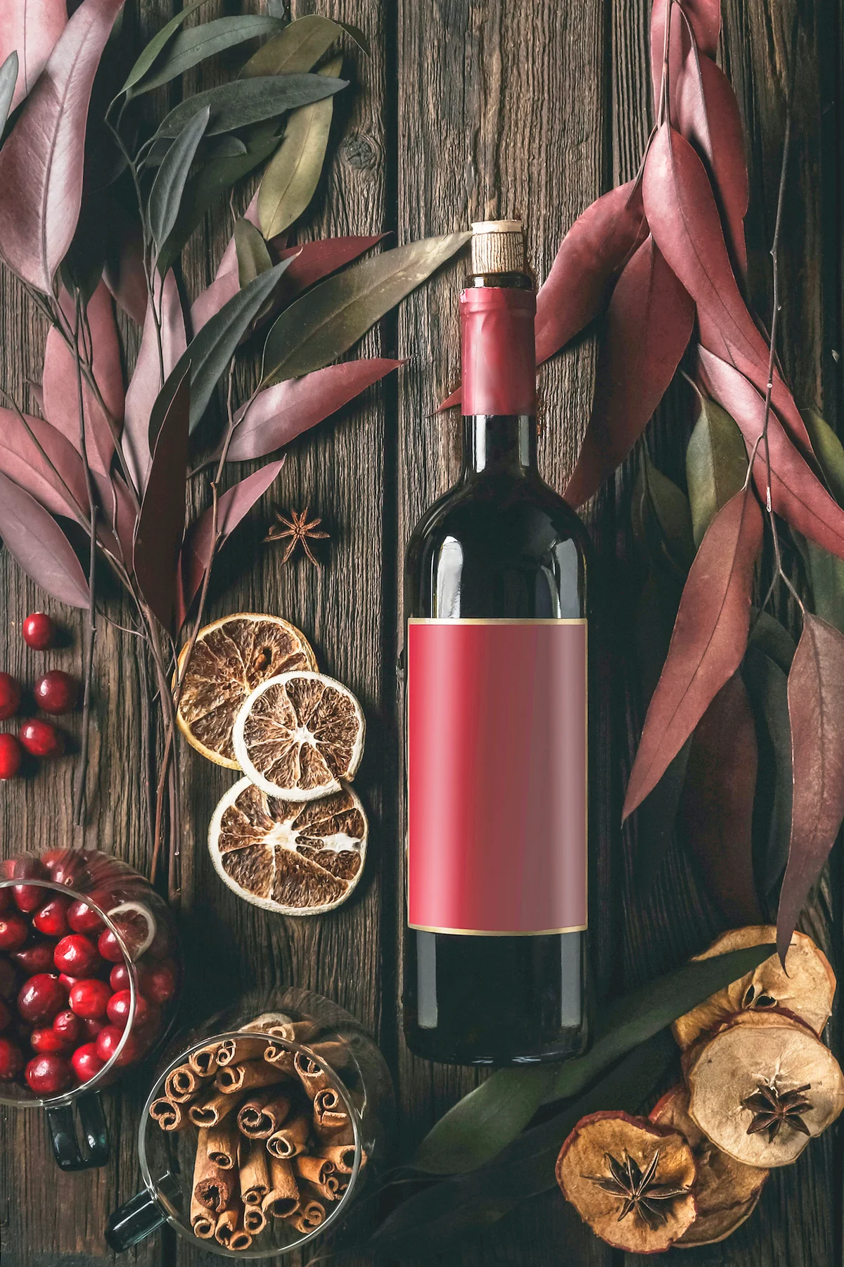 Red wine bottle and mulled wine spices and ingredients on dark wooden background