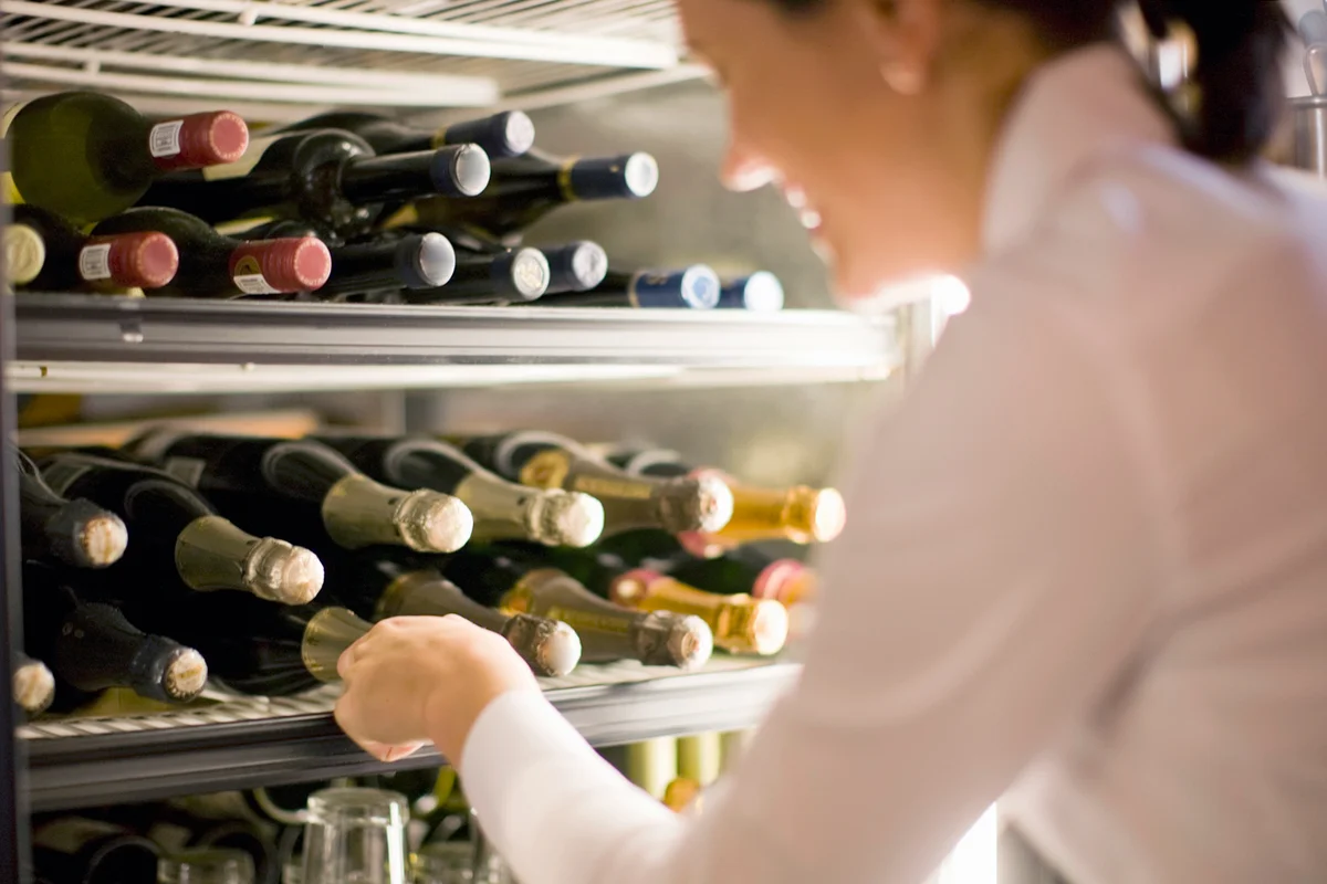 Waitress reaching for champagne in the fridge