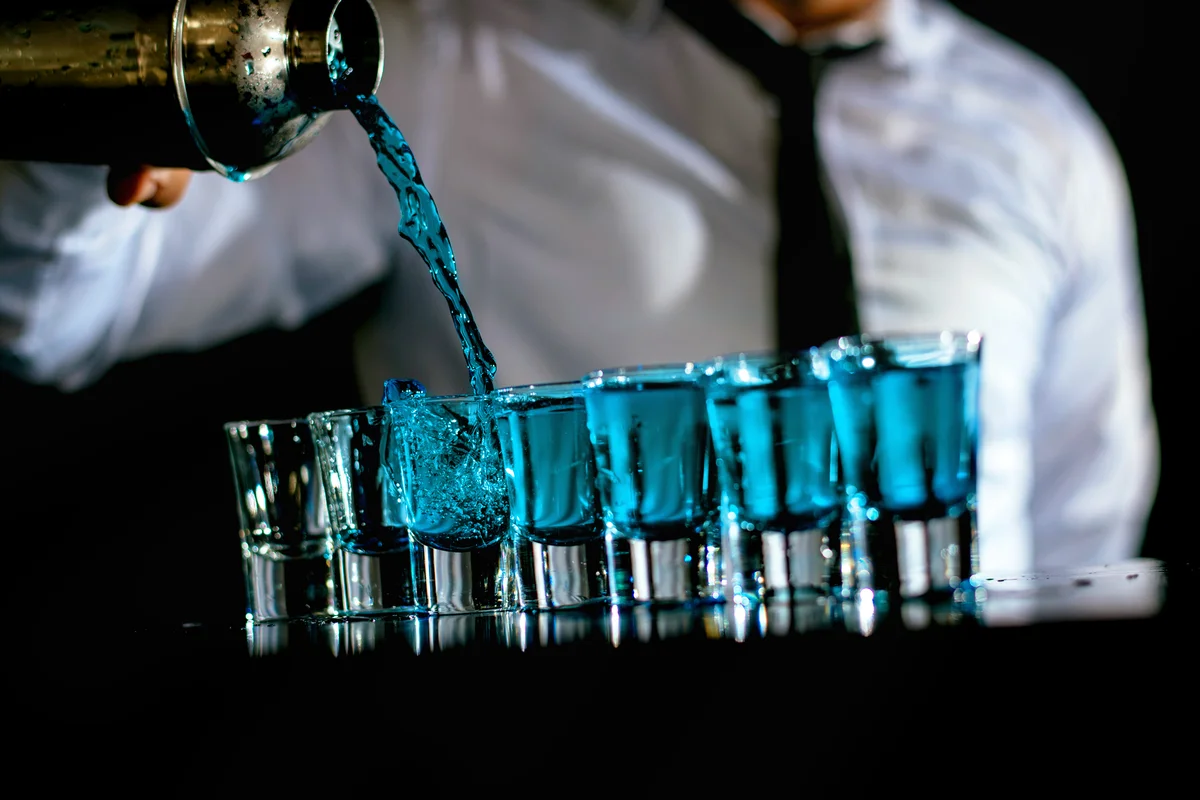 Bartender preparing blue cocktail shots