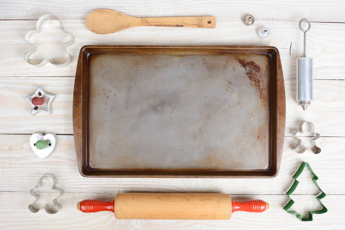 Items for baking cookies surrounding an empty baking sheet