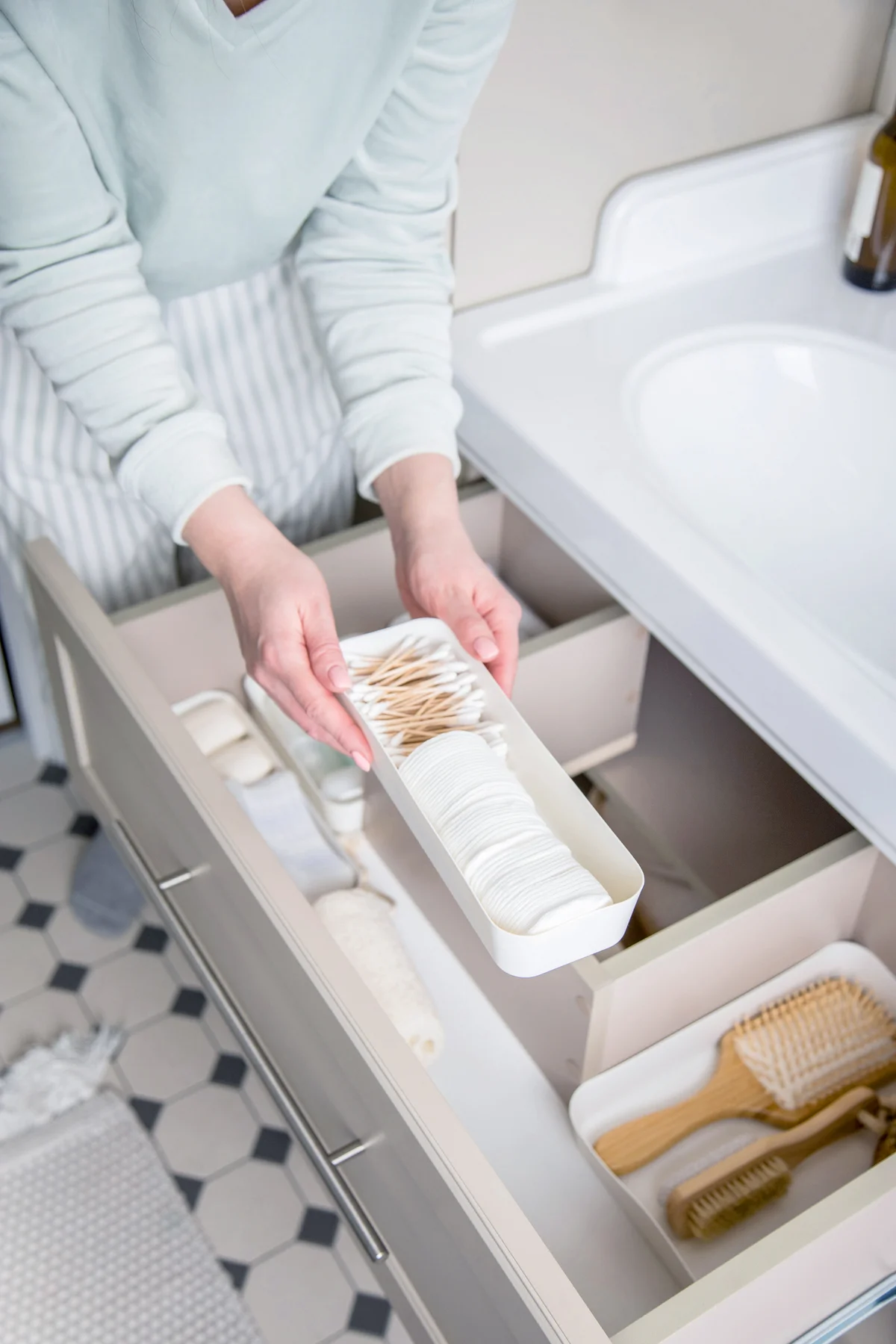 Woman organizing toiletries in drawer in the bathroom