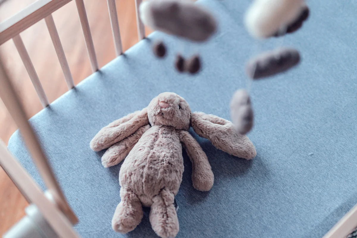Empty baby nursery with stuffed bunny and handmade hanging mobile