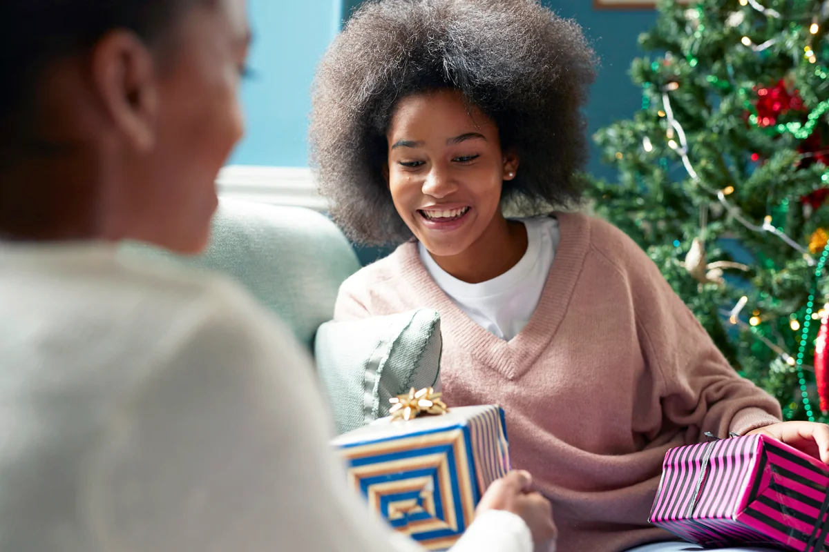 Girl giving Christmas present to sister at home