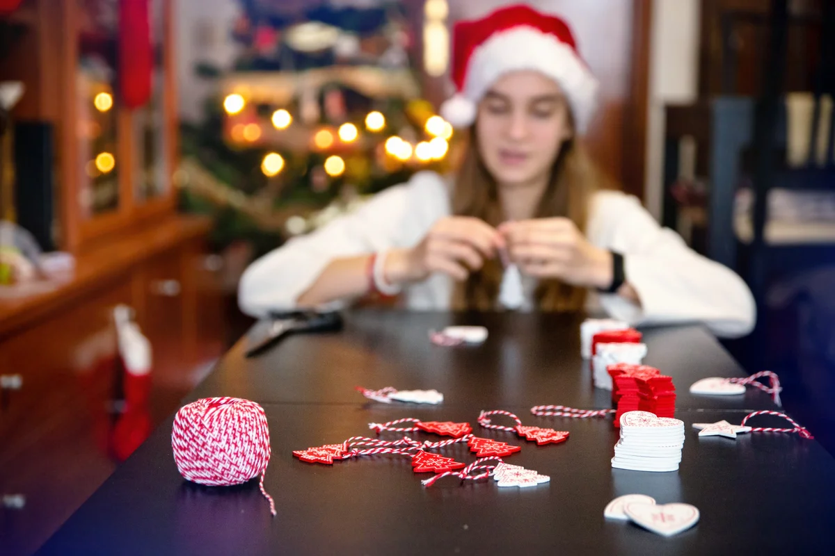 Wooden Christmas ornaments with a ribbon that a happy girl dressed in Santa Claus's hat