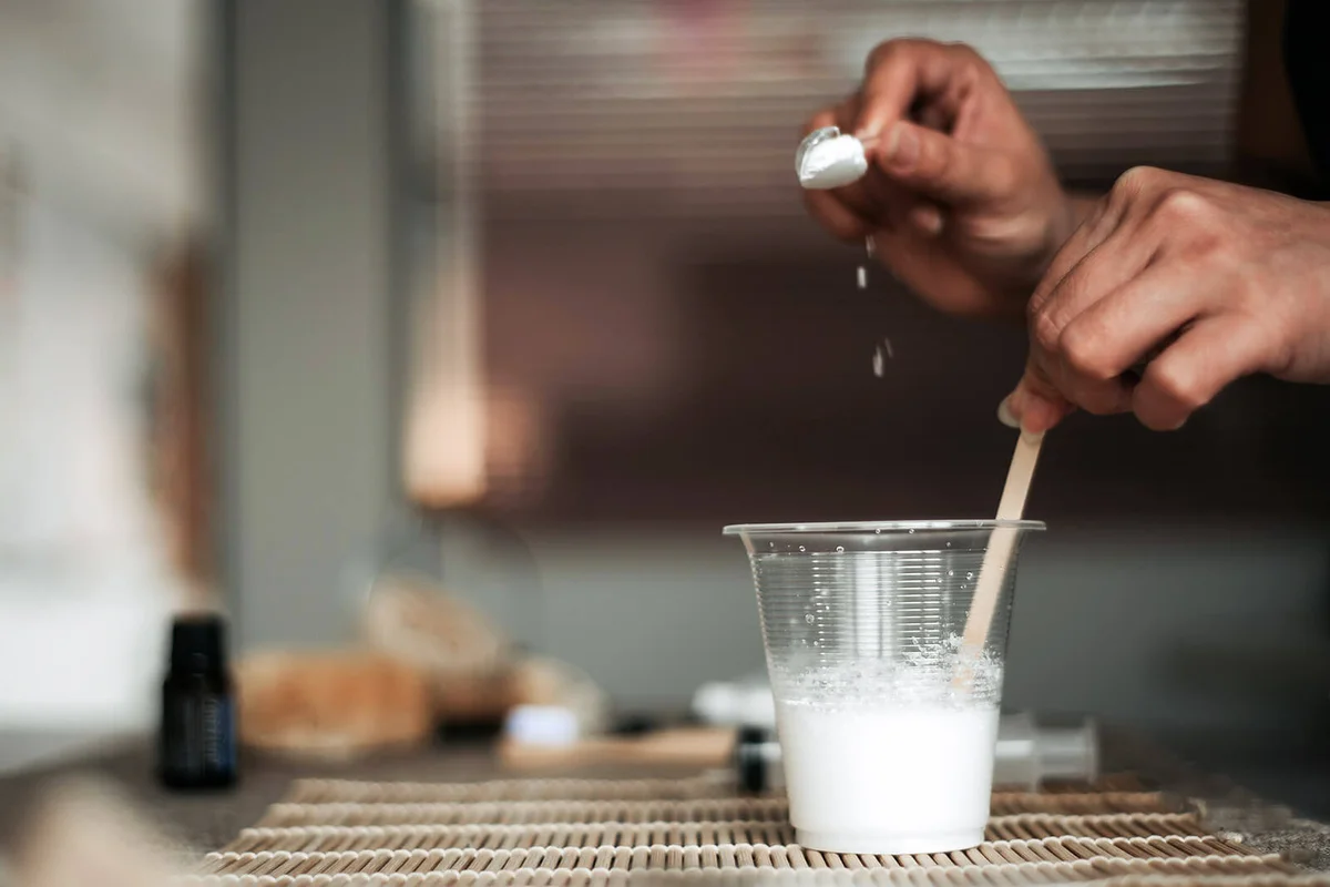woman pouring baking soda to a water cup
