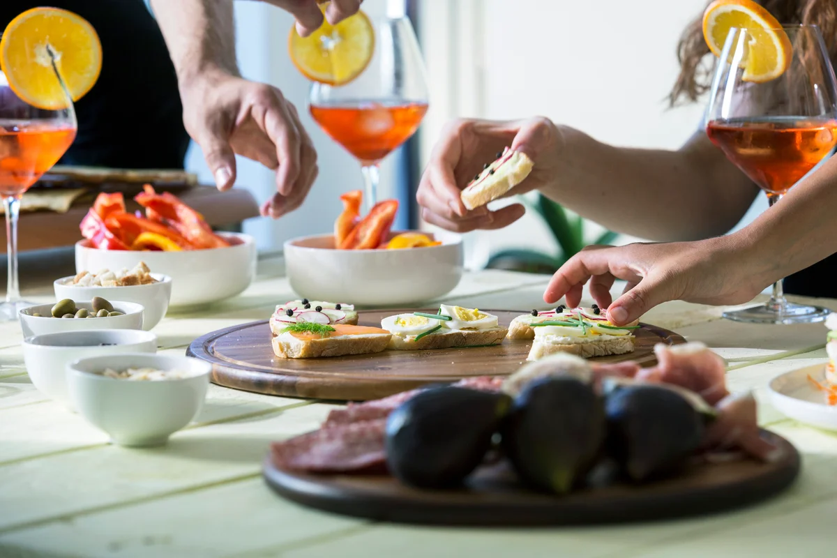 Hands reaching for appetizers on table