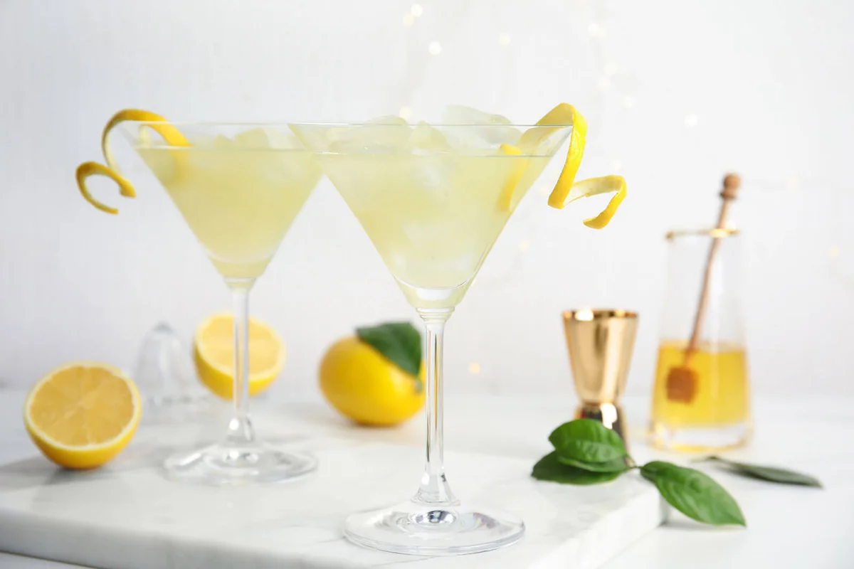 Delicious bee`s knees cocktails and ingredients on white table | Photo 245846022 © Chernetskaya | Dreamstime.com