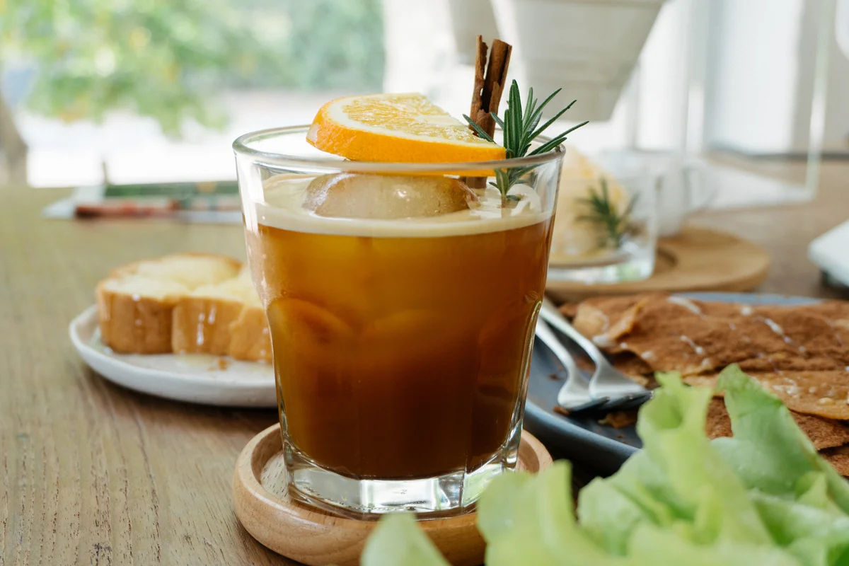 apple pie cocktail with orange slice and rosemary sprig garnish