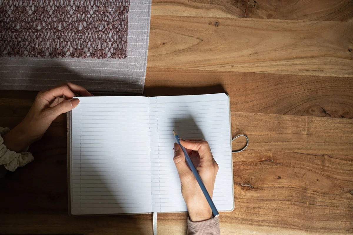Woman writing and making notes in her blank stripped notepad