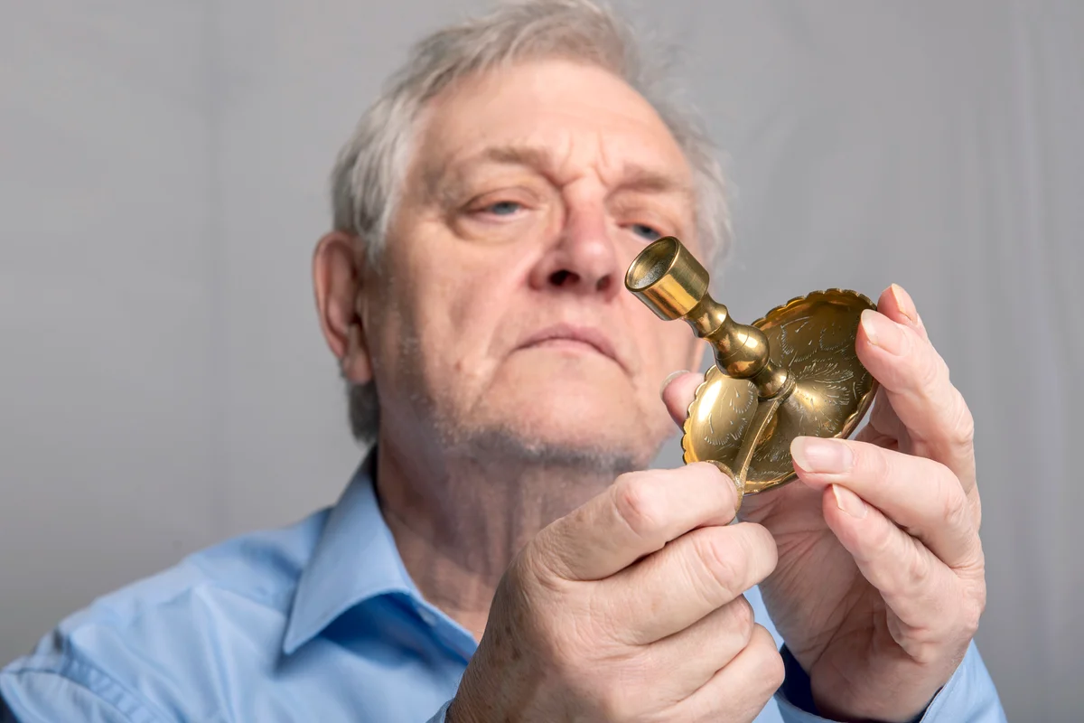 Senior man examining antique candle holder