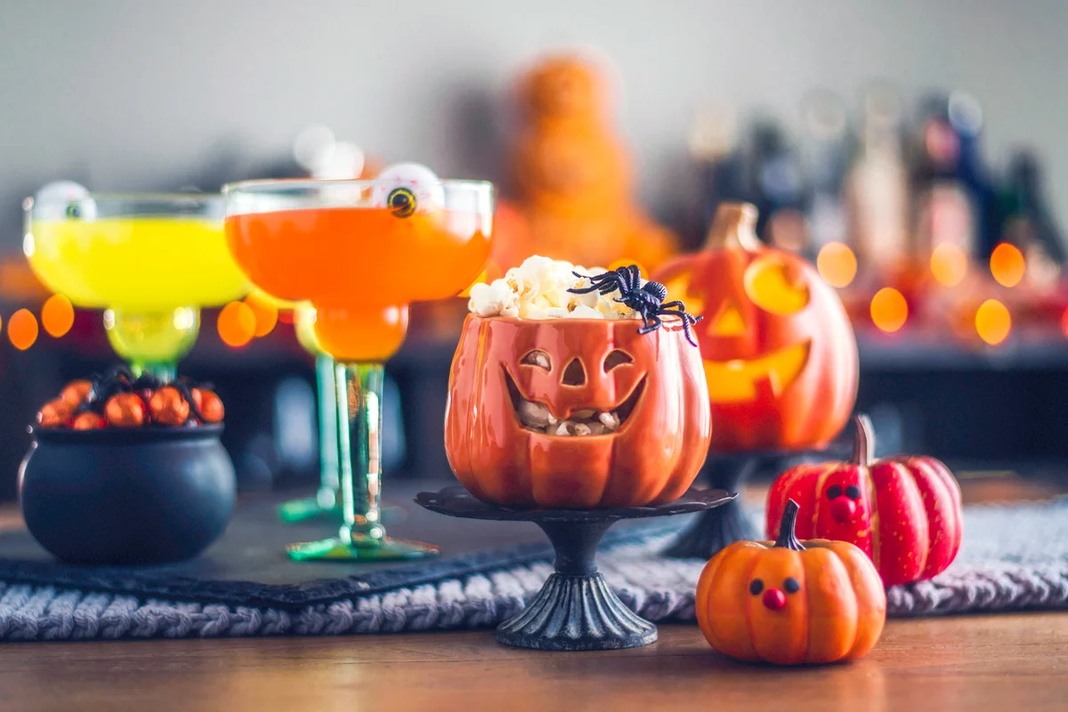 Vibrant halloween colored martinis with cauldron of candy